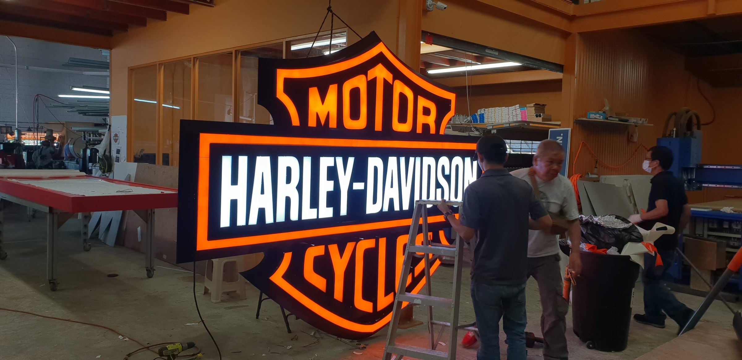 Sign King fabricators assembling a large illuminated channel-letter sign in the Harmon shop